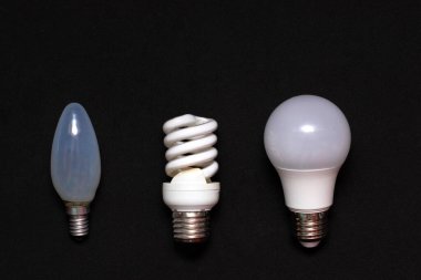 Three generations of light bulbs on a black background: ordinary light bulb, helium and LED lamps. Place for text, copy space. clipart