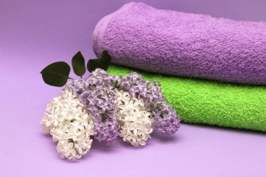 Bir yığın havlu ve bir dal çiçek açan leylak. Spa tedavileri, aromaterapi.