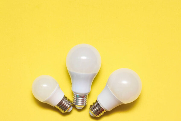 Three LED lamps of different sizes on a yellow background. Electricity Saving Concept. Place for text, copy space.