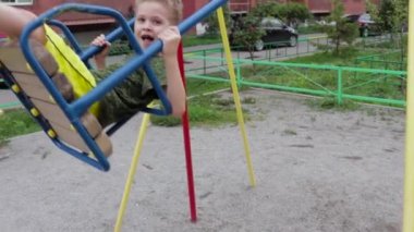 Okul öncesi bir çocuk salıncakta sallanıyor oyun alanında, videoda