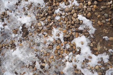 Küçük çakıl taşları ve eriyen kar