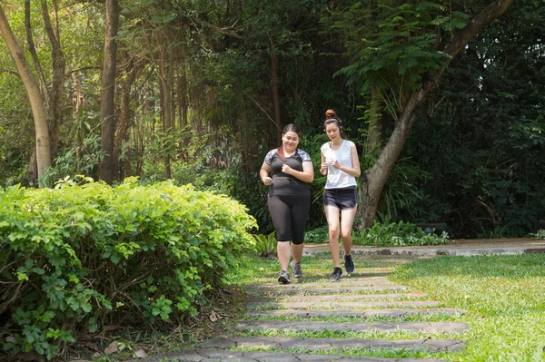 Femme grosse et sportive exercice en faisant du jogging dans le parc, ils courent pour la santé et perdre du poids . — Photo