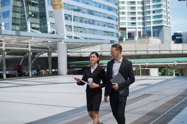 Mujer de negocios asiática y hombre de negocios caucásico usan traje caminar en la ciudad y discutir el futuro de los negocios . — Foto de Stock