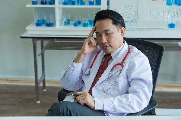 hastanede sandalyede oturan stresli doktor, o aşırı çalıştıktan sonra baş ağrısı