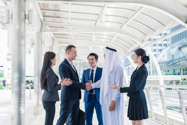 Empresario multiétnico de pie y estrechando la mano en la ciudad para tener éxito en la Cooperación Empresarial. multicultura de empresarios, africanos, caucásicos y asiáticos . — Foto de Stock