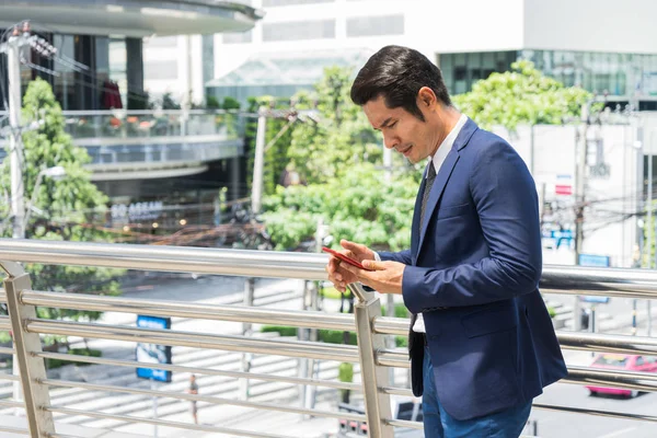 Seriamente preocupado hombre de negocios chatear con un amigo en el teléfono inteligente en la ciudad. concepto de tecnología y fracaso empresarial . — Foto de Stock