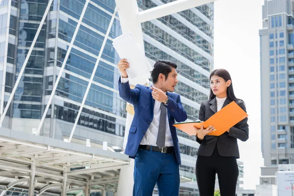 angry businessman stand and holding document on hand, boss blaming secretary for work mistakes.