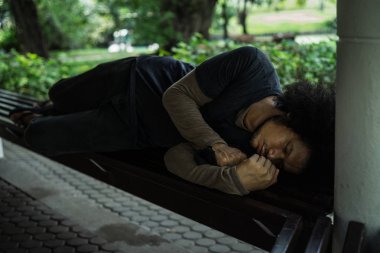 Zavallı evsiz adam ya da parkta bir koltukta uyuyan mülteci. sosyal belgesel kavramı.