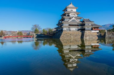 Kırmızı köprü, mavi gökyüzü ve hendek üzerinde kaleyansıması ile Matsumoto kale güzel. Matsumoto, Nagano Prefecture, Japonya