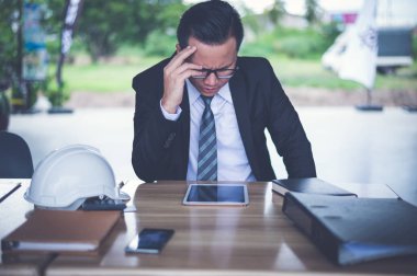 işadamı vurguladı ve üzüntü, o oturan ve elini şantiyede başını clasped, iş başarısızlık ve mali sorun kavramı.