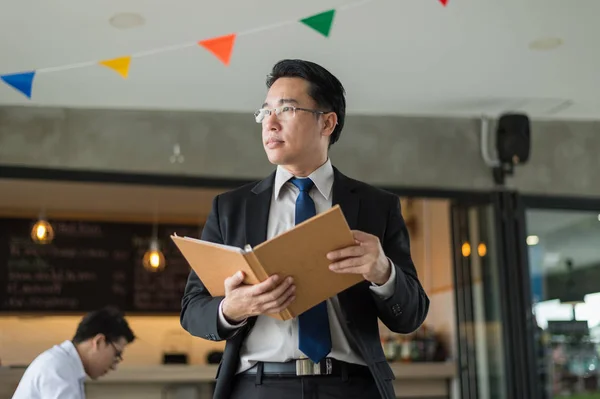 Hombre de negocios asiático en traje negro, que de pie y la celebración de archivo de documentos sobre el informe financiero en la mano . — Foto de Stock