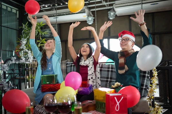 Asiático homem e mulher se divertindo na festa de Natal, eles estão sorrindo e jogando balões coloridos, Conceito de Natal ou festa de Ano Novo . Imagens De Bancos De Imagens Sem Royalties