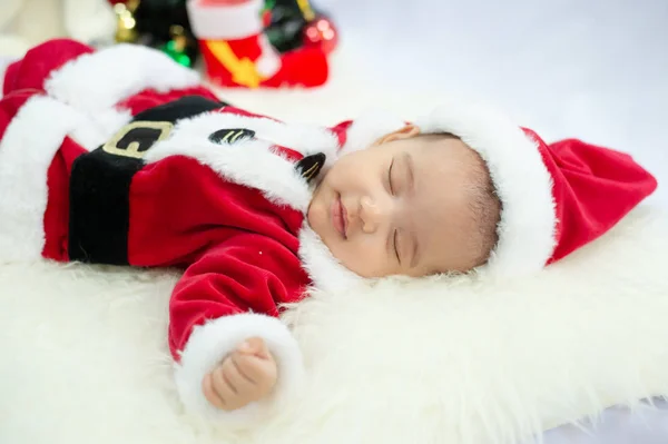 Bébé fille portant le costume rouge du Père Noël dormir sur tapis de fourrure blanche. Concept de fête de Noël et du Nouvel An . — Photo