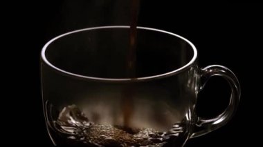 Siyah arkaplandaki bardaklara çay dökülüyor