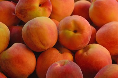 Bir demet şeftali üst üste yığılmış. Şeftaliler olgunlaştı ve yenmeye hazır.