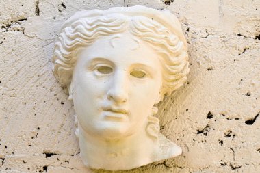 Gözü morarmış bir kadının beyaz heykeli. Heykel bir duvarda.