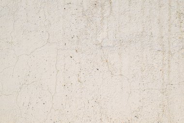 Bir sürü deliği ve çatlağı olan beyaz bir duvar. Duvar çok pürüzlü ve düzensiz.
