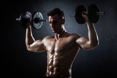 Atletik gömleksiz genç erkek fitness modeli dumbbells ile