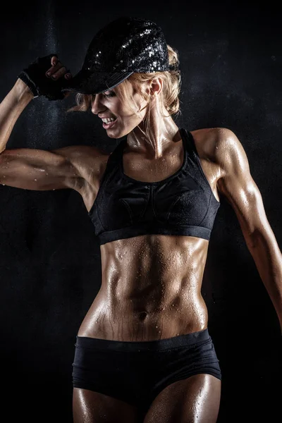 Beautiful athletic woman in cap posing on dark — Stock Photo, Image
