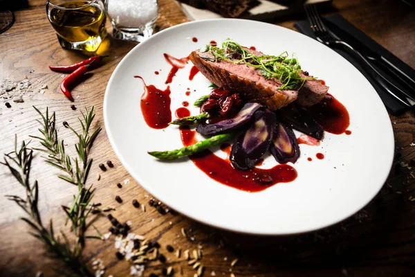 Peito de pato com espargos, salada e molho em prato branco. Delicioso alimento saudável grelhado e assado filé de pássaro closeup servido em uma mesa para almoço na cozinha moderna restaurante gourmet . — Fotografia de Stock