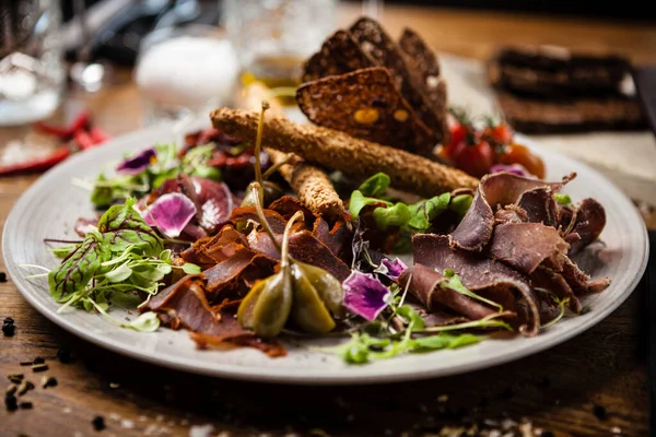 Bandeja de carne para dos: Brisket de ternera envejecido en seco, filete de pato, paté de hígado de ternera, striploin de cordero, mermelada de arándanos y grissini. Aperitivo tradicional italiano primer plano servido en el restaurante gourmet moderno —  Fotos de Stock