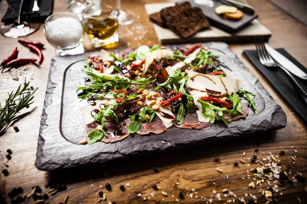 Rundvlees carpaccio geserveerd op een plank. Heerlijke gezonde Italiaanse traditionele antipasti snacks closeup geserveerd voor de lunch met wijn in modern gastronomisch restaurant. — Stockfoto