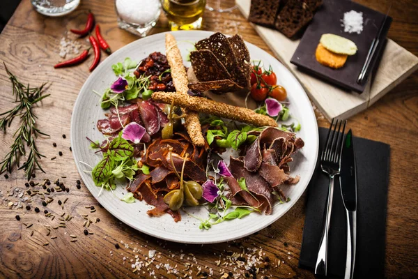 Prato de carne para dois: peito de vaca envelhecido a seco, filé de pato, pato de fígado de vaca, striploin de cordeiro, geléia de cranberry e grissini. Italiano tradicional aperitivo comida closeup servido no moderno restaurante gourmet — Fotografia de Stock