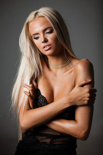 Porträt einer blonden jungen Frau mit wunderschönem Make-up und Frisur in einem schwarzen Spitzenkleid steht auf grauem Hintergrund. Modemodel posiert in eleganter Kleidung im Studio — Stockfoto