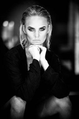 Rahatlama ve spa konsepti. Siyah mayo giymiş seksi, şık bir kadının portresi. Islak saçlı ve makyajlı kadın doğal ışıkta yüzme havuzunun yanındaki sandalyede poz veriyor. Siyah ve beyaz, tek renkli.