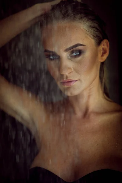 Conceito de relaxamento e spa. Retrato de uma senhora da moda sexy em um maiô preto. Mulher com cabelo molhado e maquiagem posa no chuveiro perto da piscina em luz natural — Fotografia de Stock