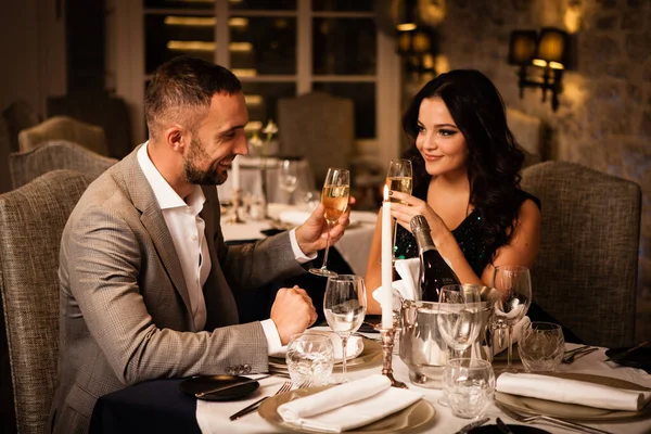 Romance et sortir ensemble concept. Jeune couple homme et femme avec des verres de champagne célébrant et grillant au restaurant. Deux personnes hommes et femmes en costume de soirée élégant et robe sur le dîner romantique — Photo