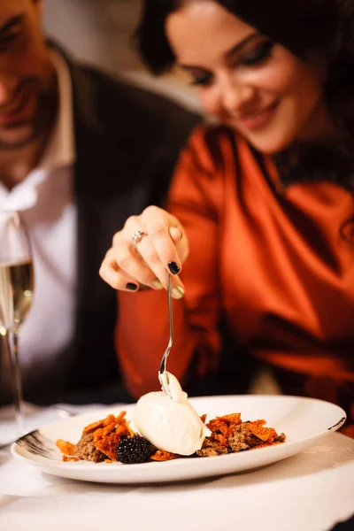 Romantizm ve flört konsepti. Genç bir çift restoranda lezzetli tatlıları kutluyor ve yiyorlar. İki kadın ve erkek şık bir gece elbisesi ve romantik bir akşam yemeği. — Stok fotoğraf