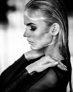 Rahatlama ve spa konsepti. Siyah mayo giymiş seksi, şık bir kadının portresi. Islak saçlı ve makyajlı bir kadın, güneş ışığında yüzme havuzunda poz veriyor. Siyah ve beyaz, tek renkli.