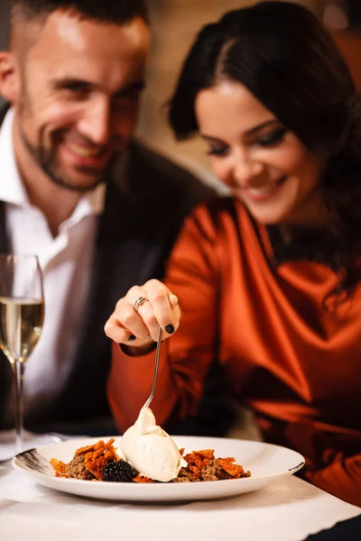Romantizm ve flört konsepti. Genç bir çift restoranda lezzetli tatlıları kutluyor ve yiyorlar. İki kadın ve erkek şık bir gece elbisesi ve romantik bir akşam yemeği. — Stok fotoğraf