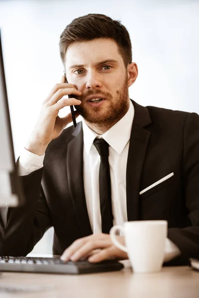 ビジネスコンセプト オフィスに立っている若いビジネスマンと非常に深刻な仕事の問題を解決する携帯電話で忙しい話 男でスーツ室内のガラス窓の背景に — ストック写真