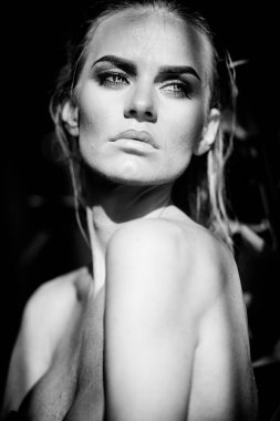 Rahatlama ve spa konsepti. Siyah mayo giymiş seksi, modaya uygun bir kadının yakın plan portresi. Islak saçlı ve makyajlı bir kadın güneş ışığında yüzme havuzunda poz veriyor. Siyah ve beyaz, tek renkli..