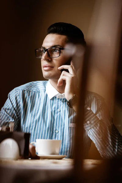 Conceito de estilo de vida comunitário LGBTQ. Jovem homossexual homem senta-se à mesa no café da cidade à moda antiga. bonito gay masculino empresário fala no um telefone enquanto tendo um intervalo no almoço — Fotografia de Stock