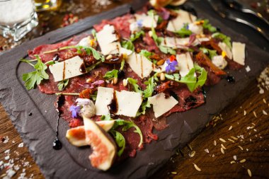 Biber, roka ve parmesanlı biftek carpaccio. Lezzetli sağlıklı İtalyan geleneksel antipasti aperatifleri yakın plan yemek servisi modern gurme mutfağında şarapla servis edilir..