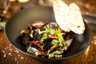 Siyah kasede beyaz şarap soslu mavi midye. Modern mutfak gurme restoranında öğle yemeği için sunulan lezzetli, sağlıklı deniz ürünleri..