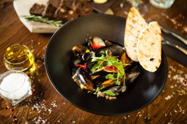 Siyah kasede beyaz şarap soslu mavi midye. Modern mutfak gurme restoranında öğle yemeği için sunulan lezzetli, sağlıklı deniz ürünleri..