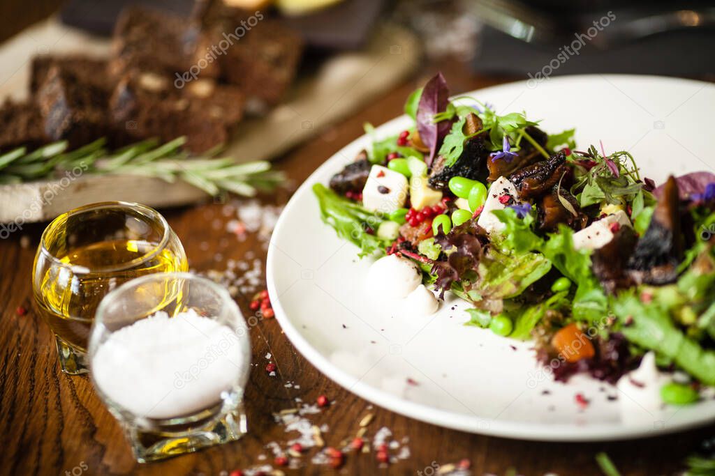 Fresh vegan salad. Avocado, couscous, melon, portobello, soybean, tofu on white plate. Delicious healthy mixed greens food closeup served on a table for lunch in modern cuisine gourmet restaurant