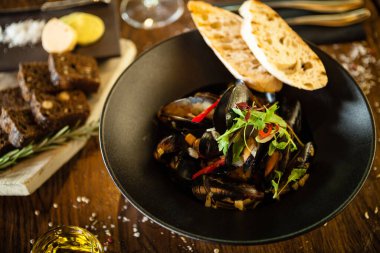 Siyah kasede beyaz şarap soslu mavi midye. Modern mutfak gurme restoranında öğle yemeği için sunulan lezzetli, sağlıklı deniz ürünleri..
