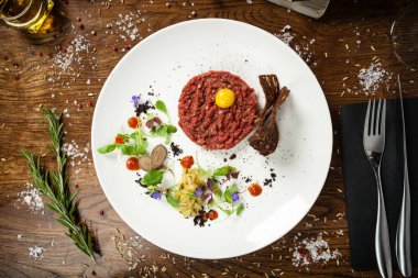 Biftek tartar. Yabanturpu kreması, siyah ekmek, beyaz tabakta baget cipsi. Modern yemek gurme restoranında öğle yemeği için bir masaya servis edilen lezzetli, sağlıklı çiğ et yemeği.