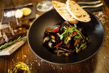 Siyah kasede beyaz şarap soslu mavi midye. Modern mutfak gurme restoranında öğle yemeği için sunulan lezzetli, sağlıklı deniz ürünleri..