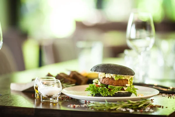 一个汉堡 黑面包 豆腐鳄梨沙拉 蛋黄酱 西红柿 新鲜沙拉 美味的健康汉堡包食物特写在现代美食餐厅的饭桌上享用 — 图库照片