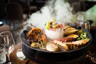 2-4 kişi için deniz ürünleri tabağı. Ahtapot, mavi midye, pişmiş yeşil midye, ızgara kaplan karidesi, ton balığı. Lezzetli deniz ürünleri modern gurme restoranında öğle yemeğinde servis edilir..