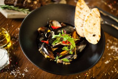 Siyah kasede beyaz şarap soslu mavi midye. Modern mutfak gurme restoranında öğle yemeği için sunulan lezzetli, sağlıklı deniz ürünleri..