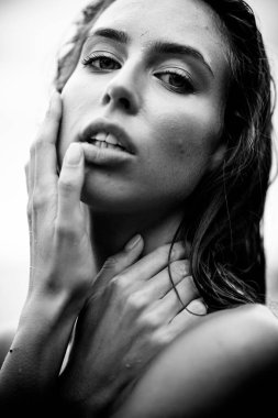 Yaz tatili konsepti. Güzel, genç, seksi bir kadın. Eğitimli, zayıf vücutlu ve ıslak saçlı. Sahilde yakın plan bir portre. Moda kadın modeli deniz kenarında poz veriyor. Siyah ve beyaz tek renk