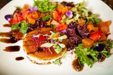 Keçi peynirli salata. Kırmızı biberli çilek-kavun salatası, elma-portakal sosu, beyaz tabakta incir reçeli. Modern yemek gurme restoranında öğle yemeği için bir masaya servis edilen lezzetli et yemekleri.