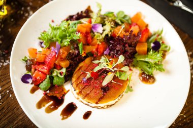 Keçi peynirli salata. Kırmızı biberli çilek-kavun salatası, elma-portakal sosu, beyaz tabakta incir reçeli. Modern yemek gurme restoranında öğle yemeği için bir masaya servis edilen lezzetli et yemekleri.